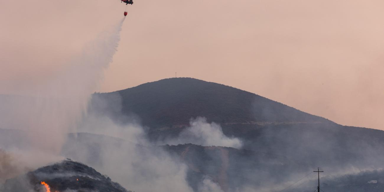 A helicopter drops water on the Border Fire in San Diego, California, on January 24, 2025 (AFP / Zoë Meyers)